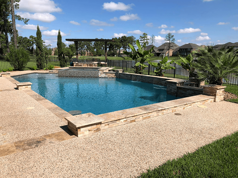 Backyard pool with stone patio and greenery.