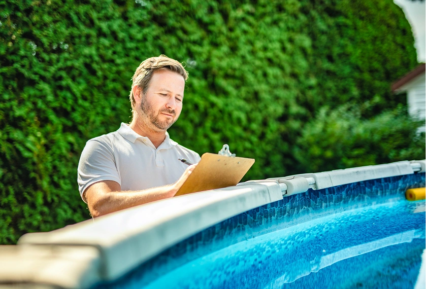 Man inspecting pool with clipboard outdoors.